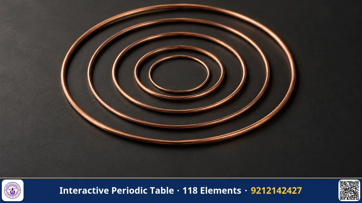 Nested concentric rings of thin copper wire of different diameters on a matte dark surface, macro photograph.